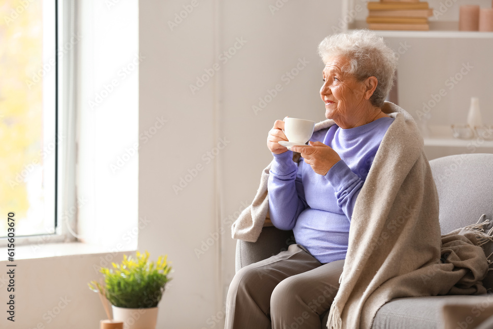 Senior woman with plaid drinking coffee on sofa at home