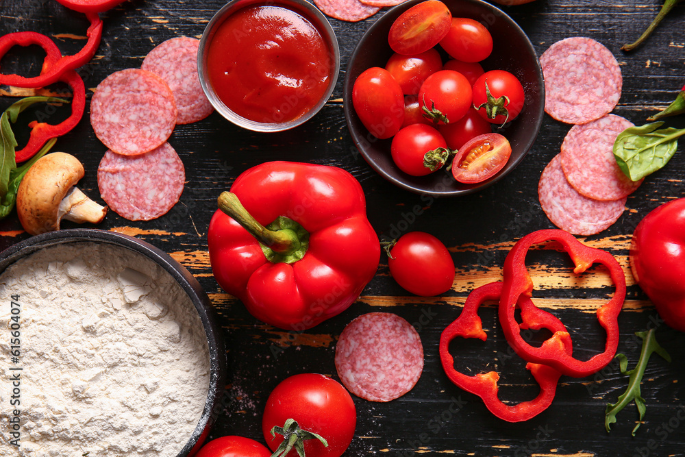 Different ingredients for preparing pizza on dark wooden background