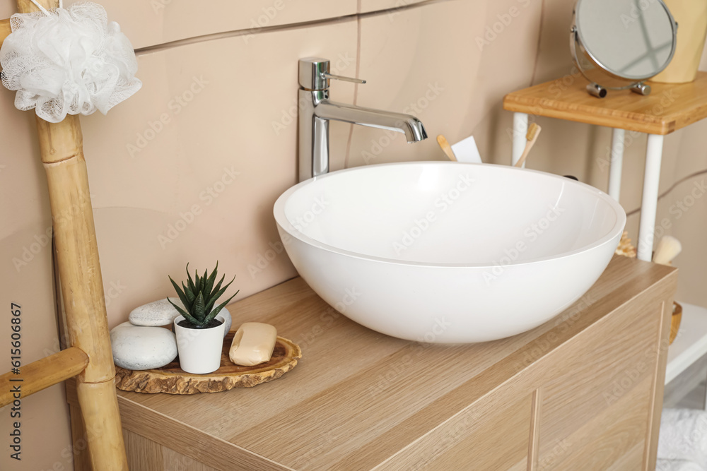 Sink bowl with bath accessories on table in bathroom