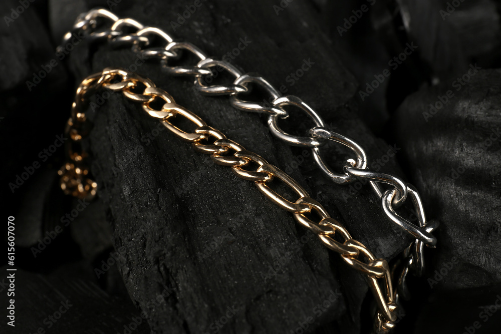 Beautiful chain bracelets on black charcoal, closeup