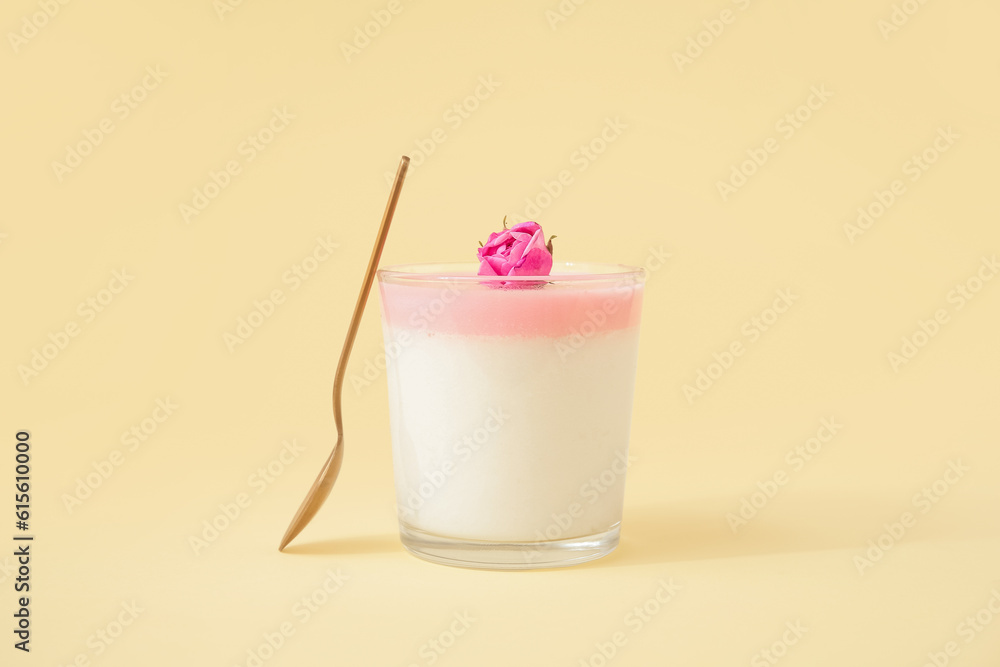 Glass of panna cotta with beautiful pink rose flower on beige background