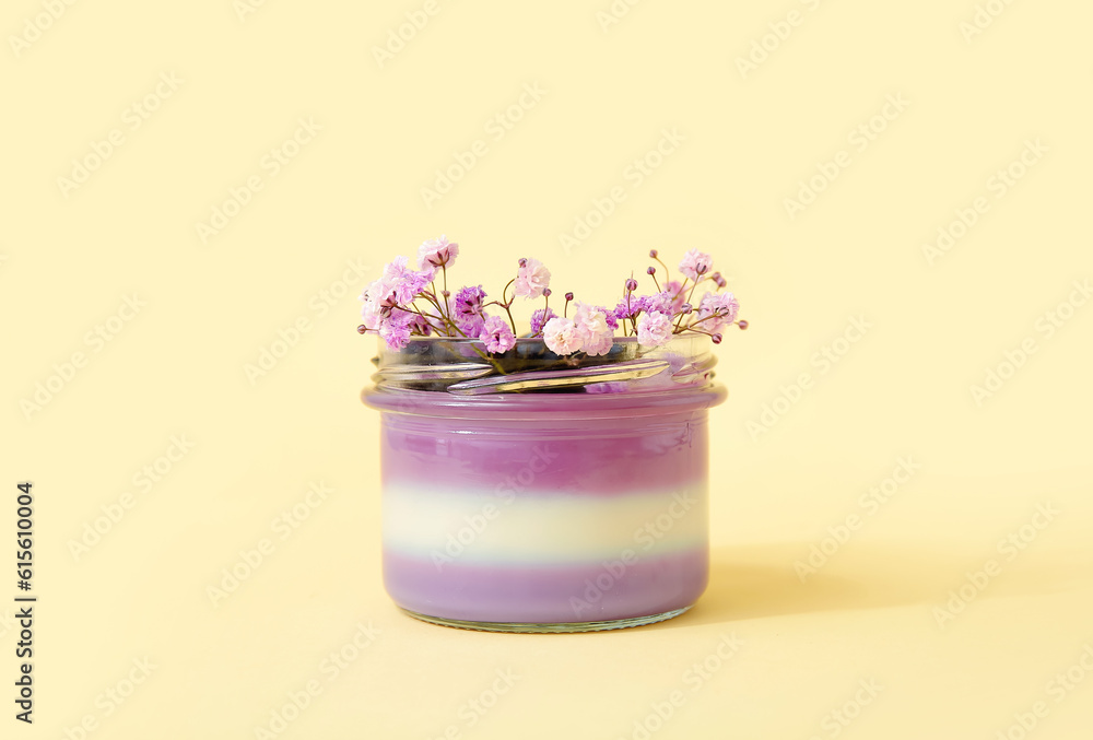 Glass of panna cotta with blueberry and beautiful gypsophila flowers on beige background