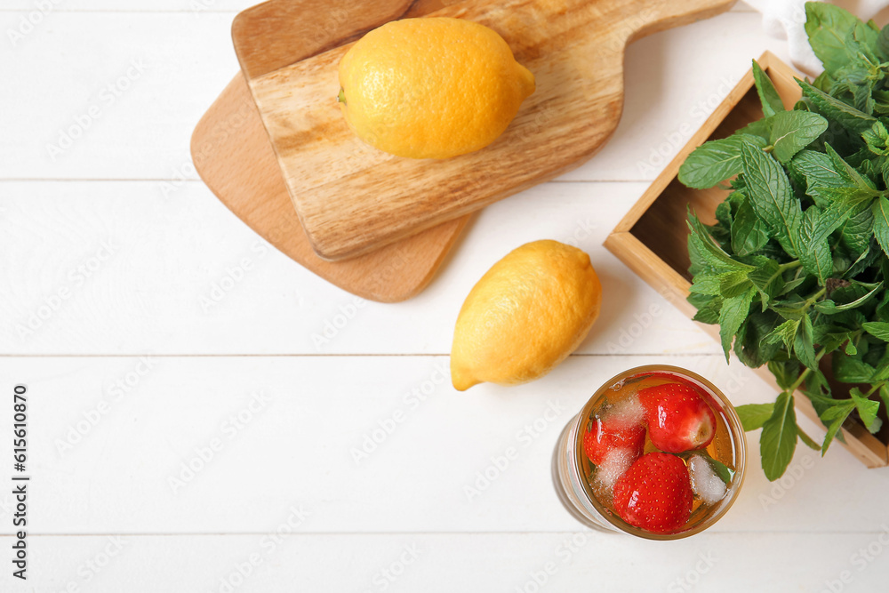 Glass of ice tea with strawberry and mint on white background