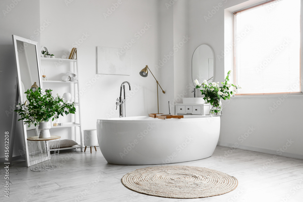 Interior of light bathroom decorated with blooming jasmine flowers in vase