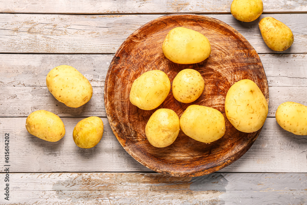 Plate with raw baby potatoes on grey wooden background