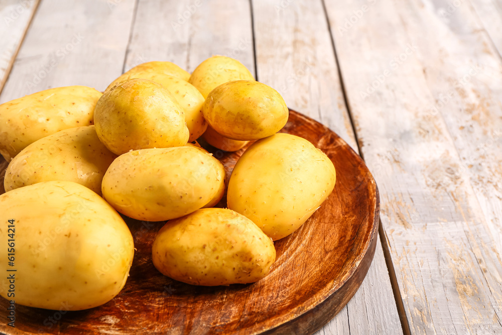 Plate with raw baby potatoes on grey wooden background