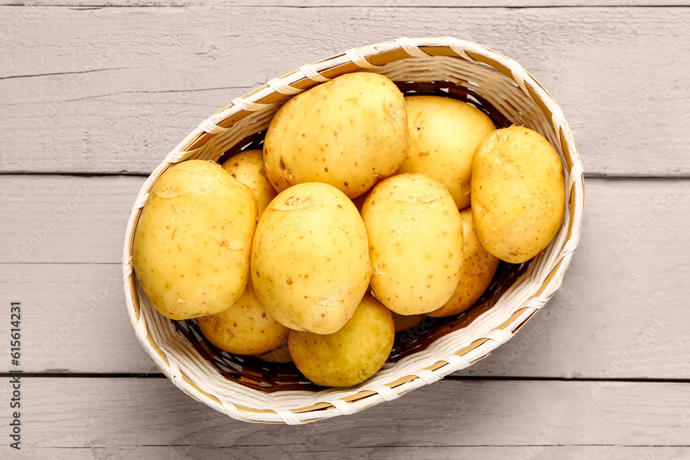 Wicker bowl with raw baby potatoes on grey wooden background