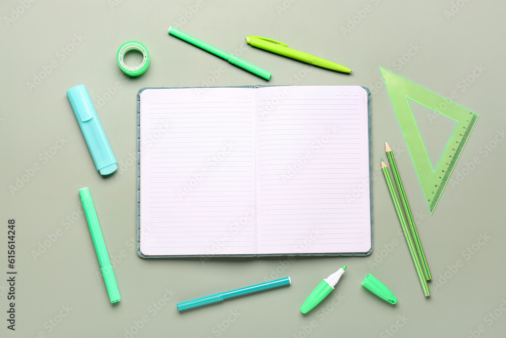 Open notebook with different stationery on grey background