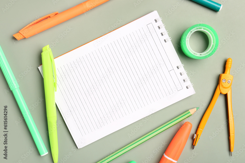 Open notebook with different stationery on grey background