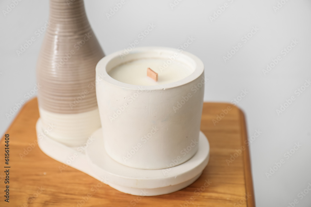 White candle on chair near light wall in room, closeup