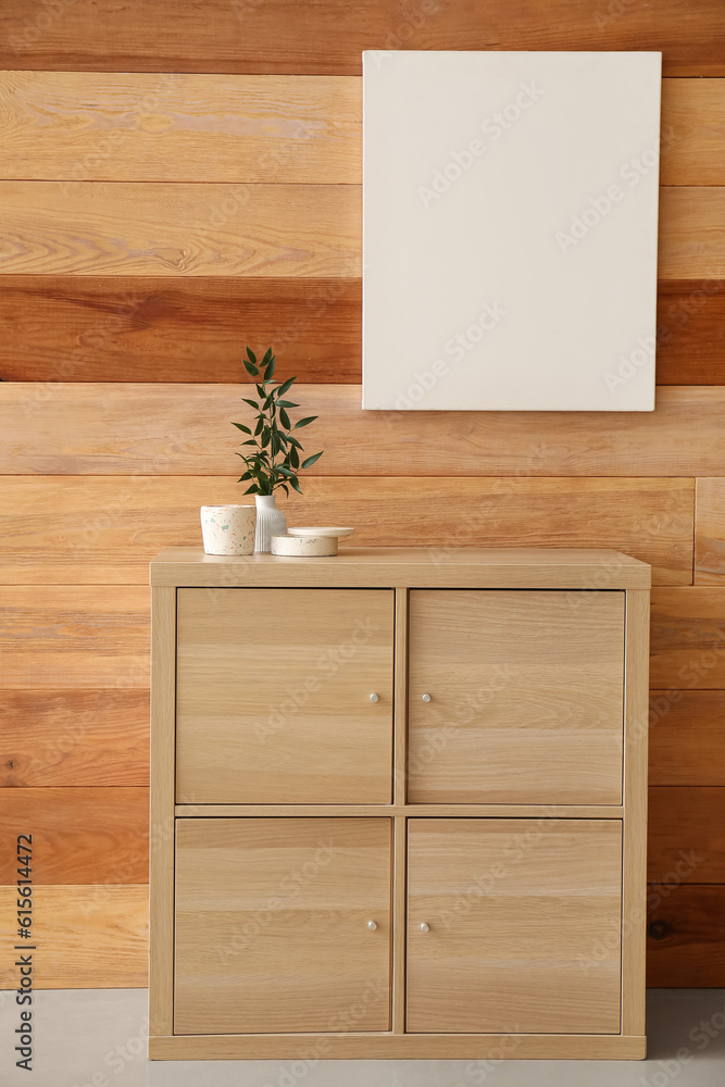 Beautiful branch, candles on shelving unit and blank frame hanging on wooden wall in room