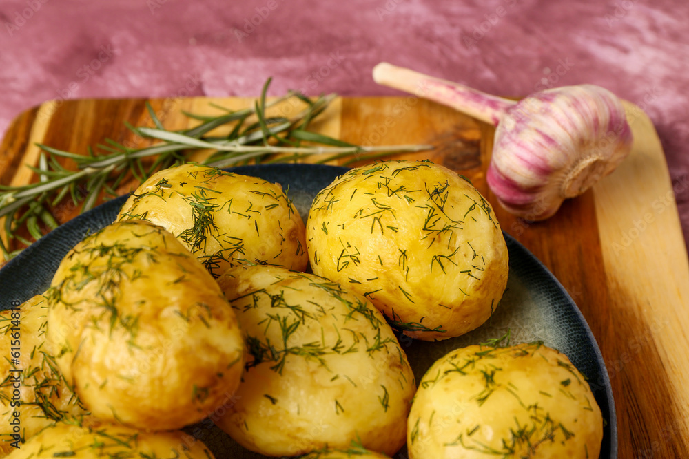 Plate of boiled baby potatoes with dill and garlic on purple background