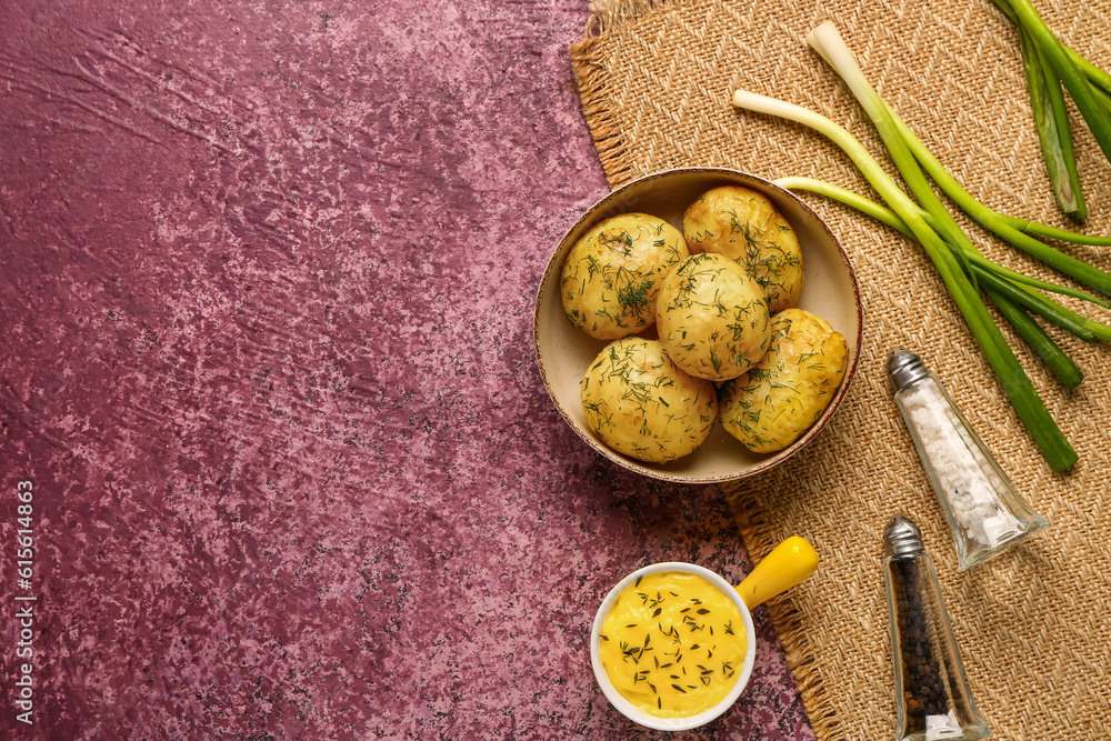 Plate of boiled baby potatoes with dill and sauce on purple background