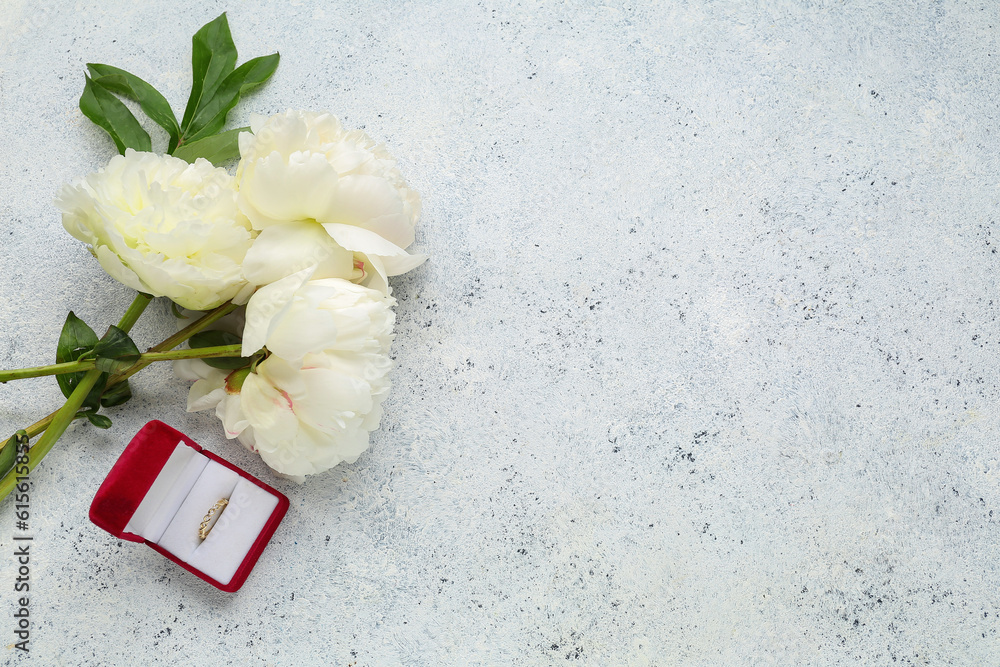 Box with beautiful female ring and peony flowers on light background