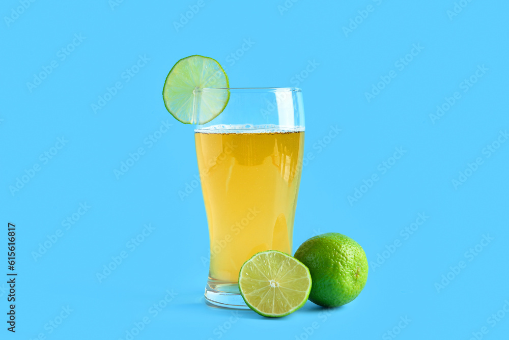 Glass of cold beer with lime on blue background