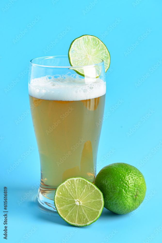 Glass of cold beer with lime on blue background