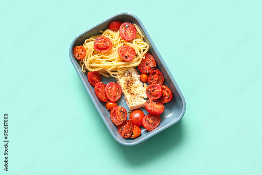 Baking dish of tasty pasta with tomatoes and feta cheese on turquoise background