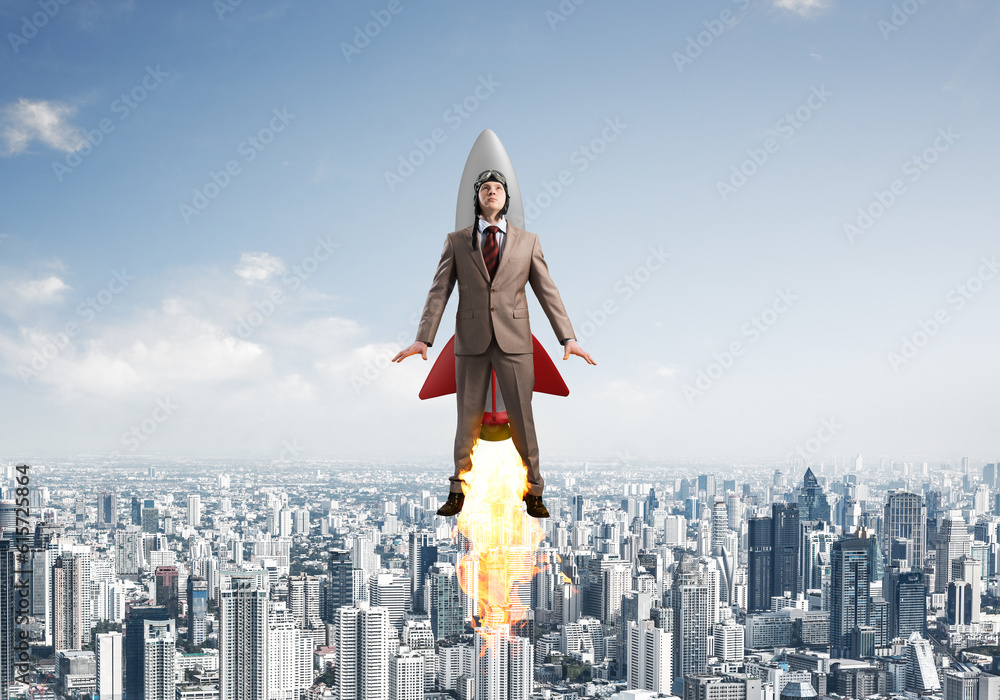 Business person in aviator hat flying on rocket