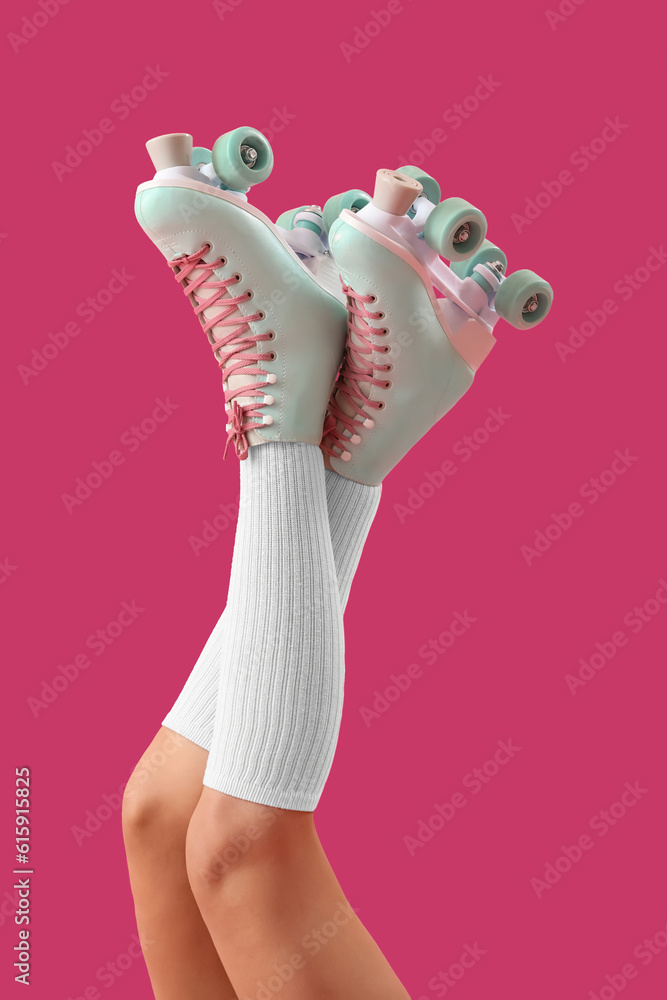 Legs of young woman in roller skates on pink background