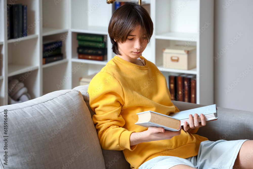 Teenage boy with books sitting on sofa at home