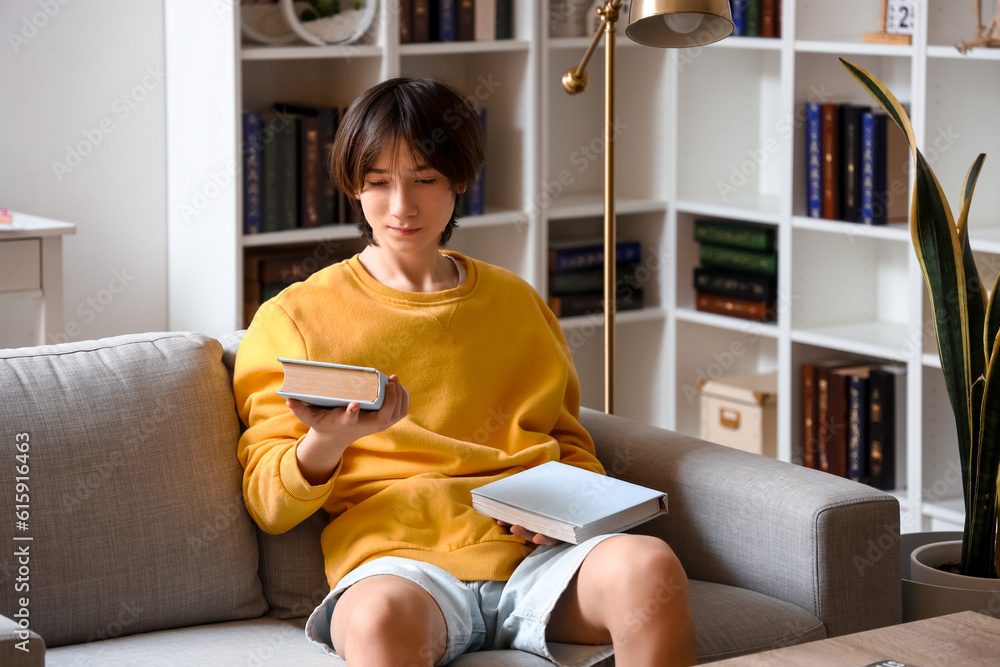 Teenage boy with books sitting on sofa at home