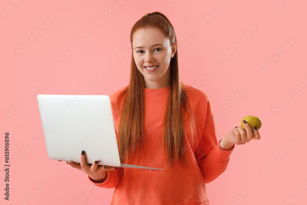 Female programmer with laptop and apple on pink background