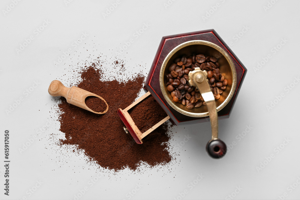 Coffee grinder with powder and scoop on white background