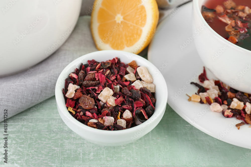 Bowl with dried fruit tea on green wooden table, closeup