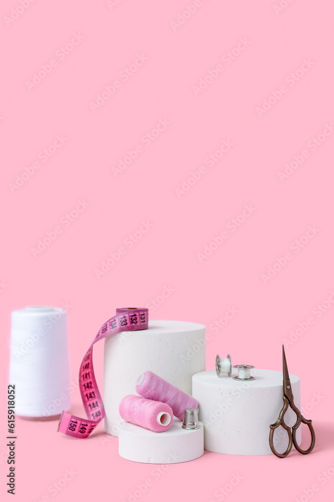 Podiums with tailors supplies on pink background