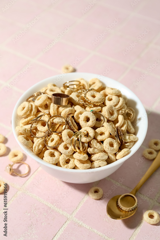 Bowl with cereal and golden rings on pink tile table