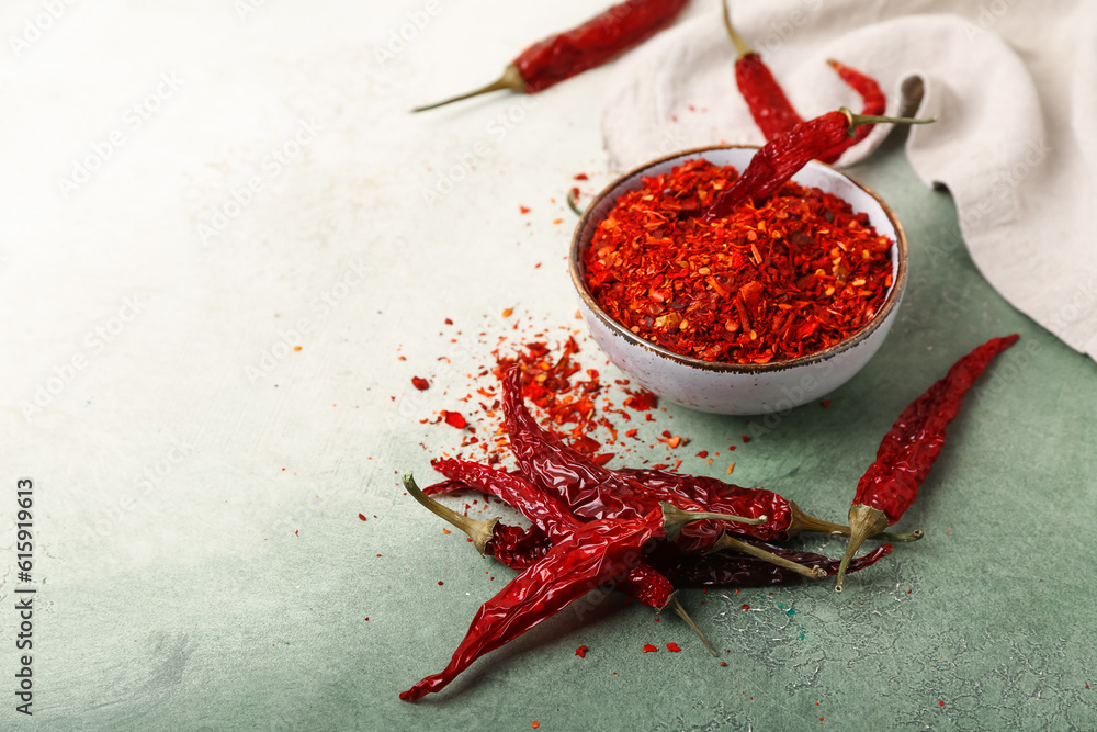 Bowl of ground peppers with dry hot chili on light background