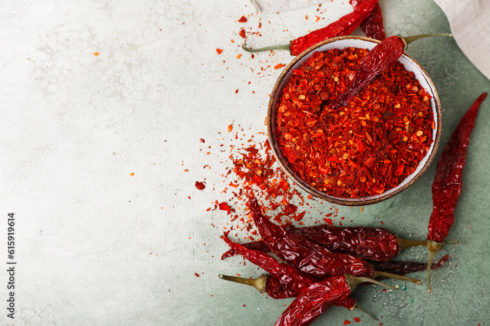 Bowl of ground peppers with dry hot chili on light background