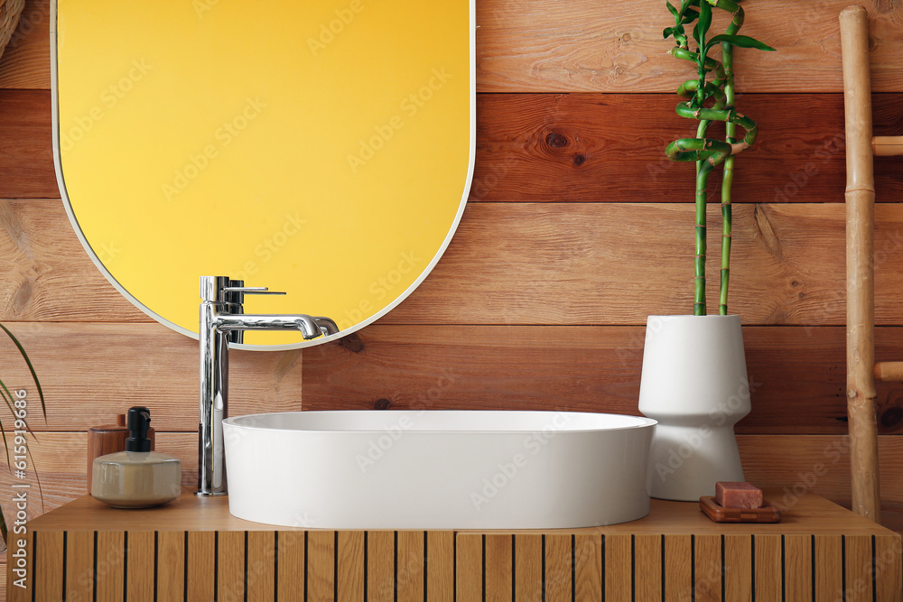 White sink and vase with bamboo stems on table in bathroom