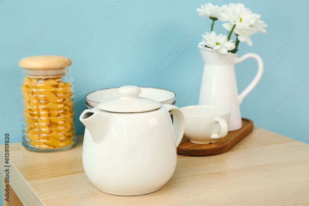 Composition with beautiful tea set, flowers and different kitchen stuff on wooden table