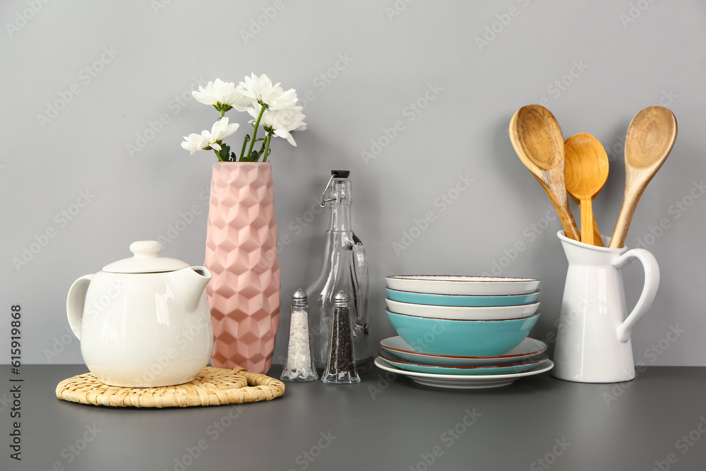 Teapot with flowers and different kitchen stuff on black table