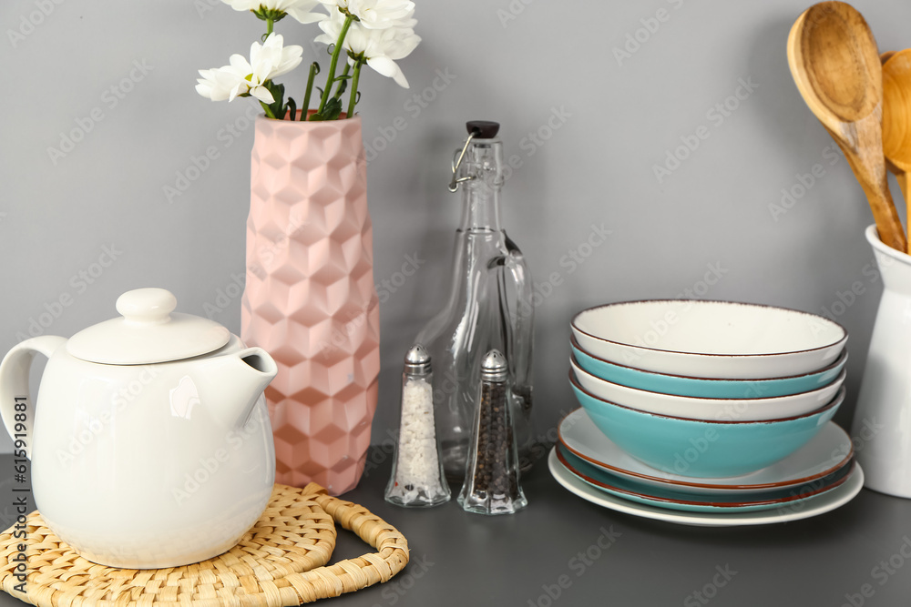 Teapot with flowers and different kitchen stuff on black table