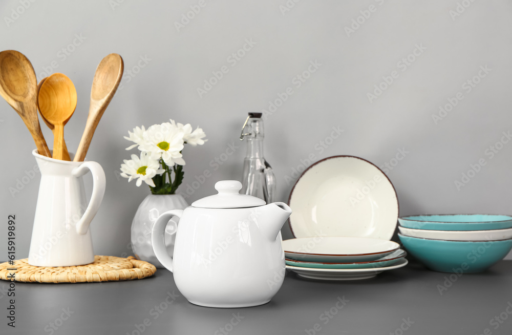 Teapot with flowers and different kitchen stuff on black table