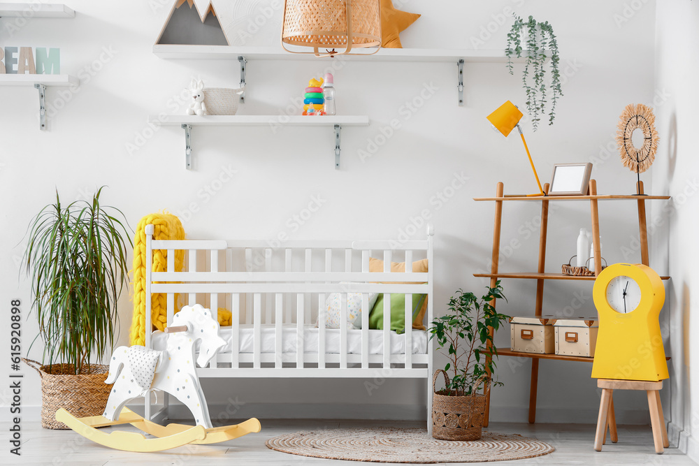 Stylish interior of childrens room with baby bed and rocking horse