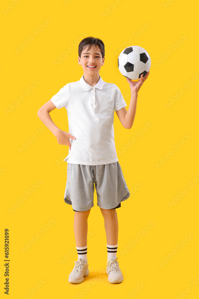 Little boy with soccer ball on yellow background