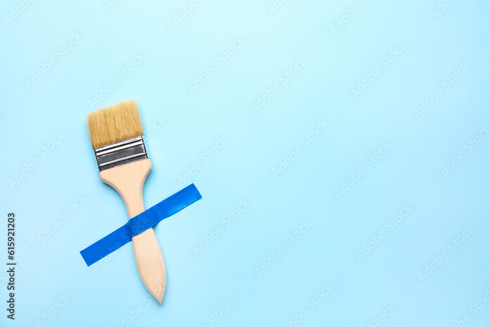 Paint brush with adhesive tape on blue background