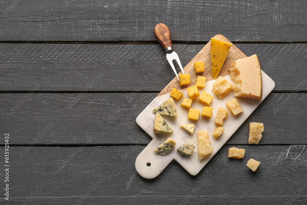 Board with pieces of tasty cheese on dark wooden background