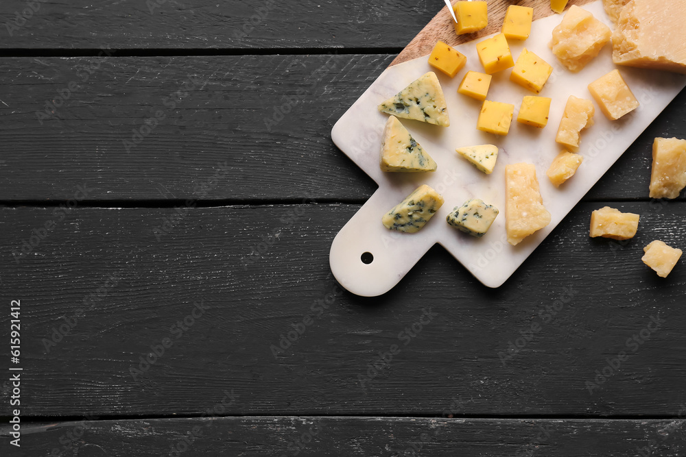 Board with pieces of tasty cheese on dark wooden background