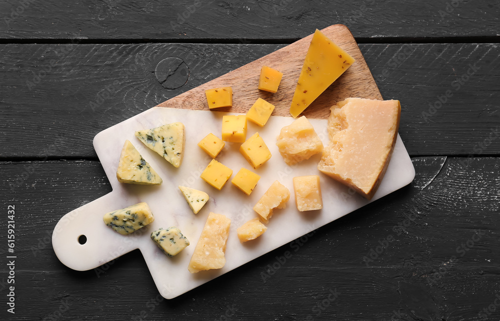 Board with pieces of tasty cheese on dark wooden background