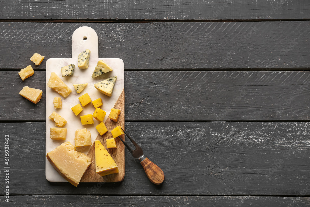 Board with pieces of tasty cheese on dark wooden background