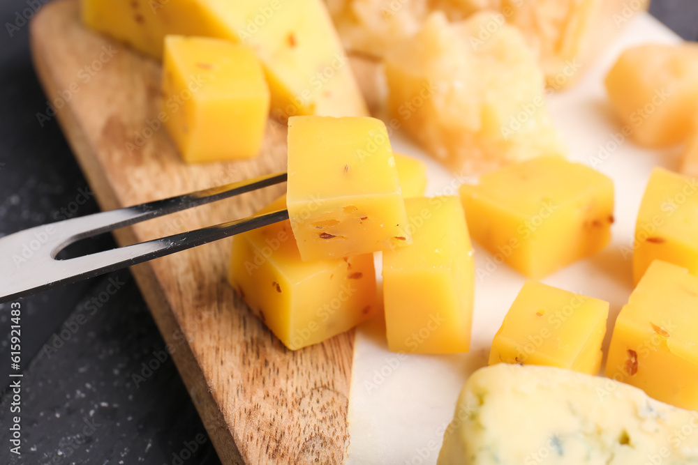 Board with pieces of tasty cheese on table, closeup