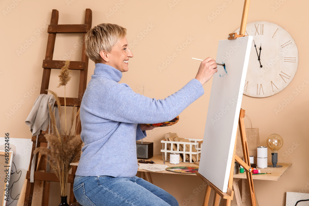 Mature female artist painting picture in  workshop