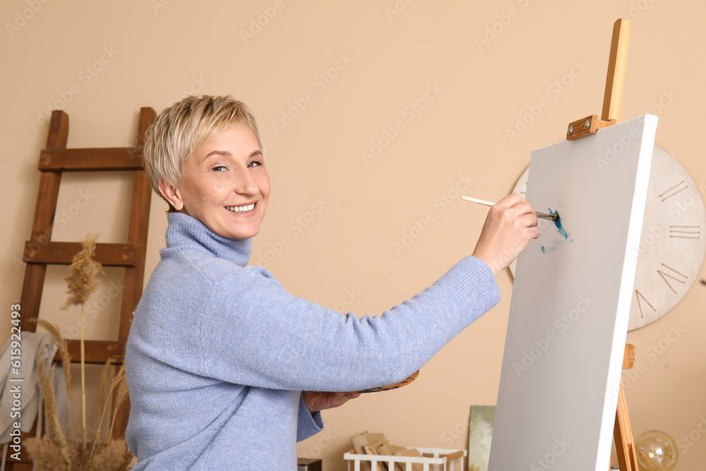 Mature female artist painting picture in  workshop