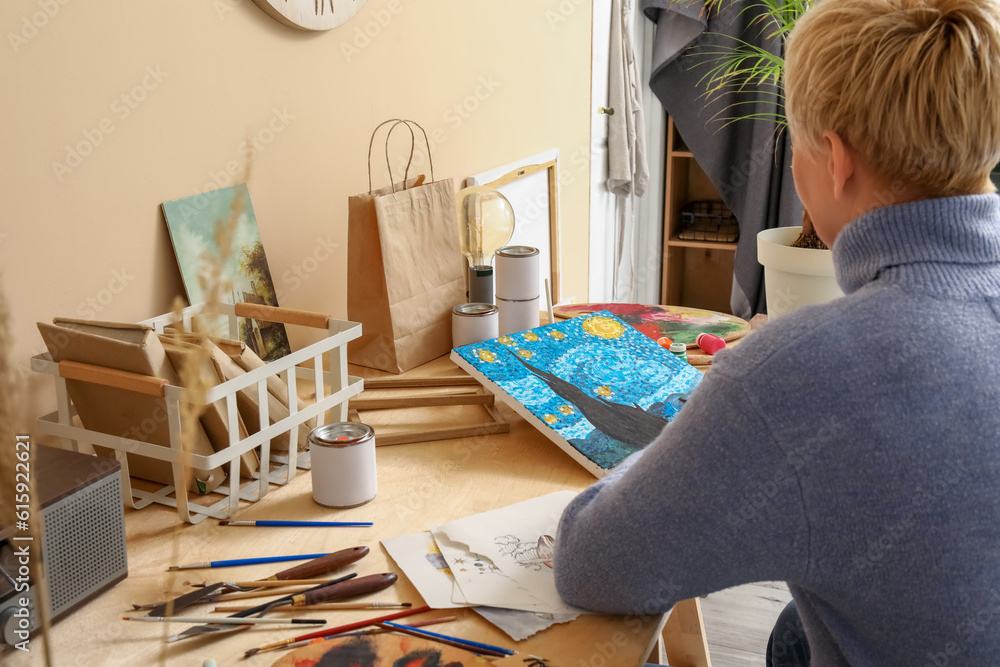 Mature female artist painting picture in  workshop