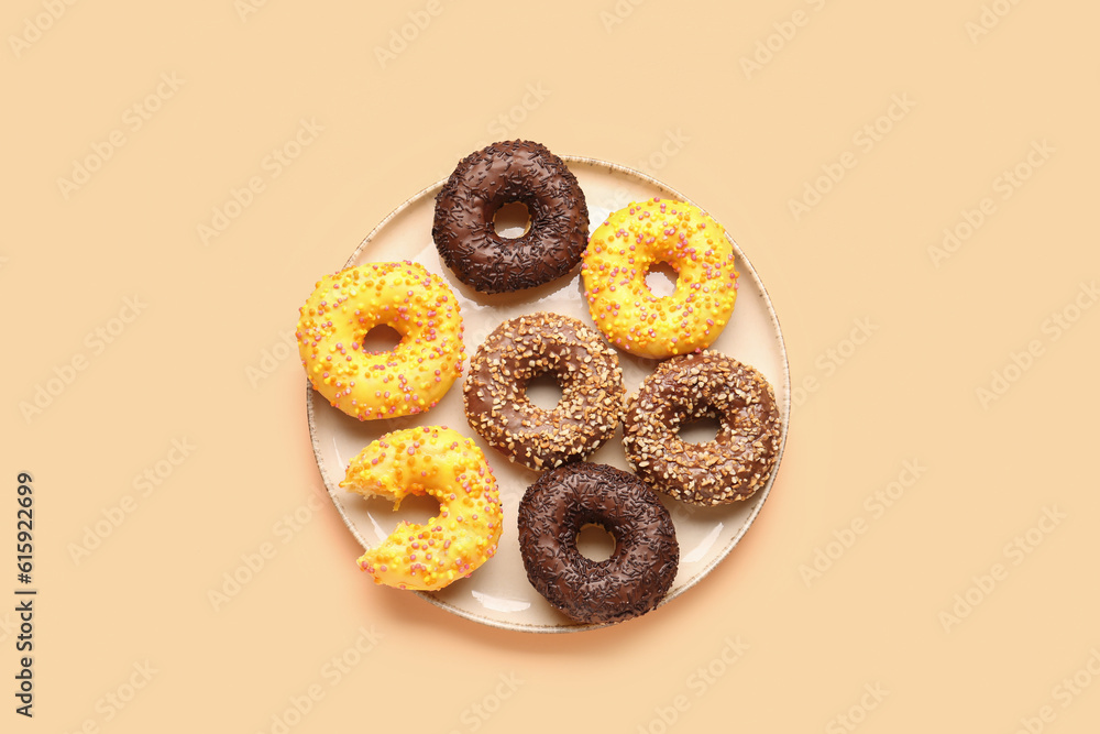 Plate with sweet donuts on beige background