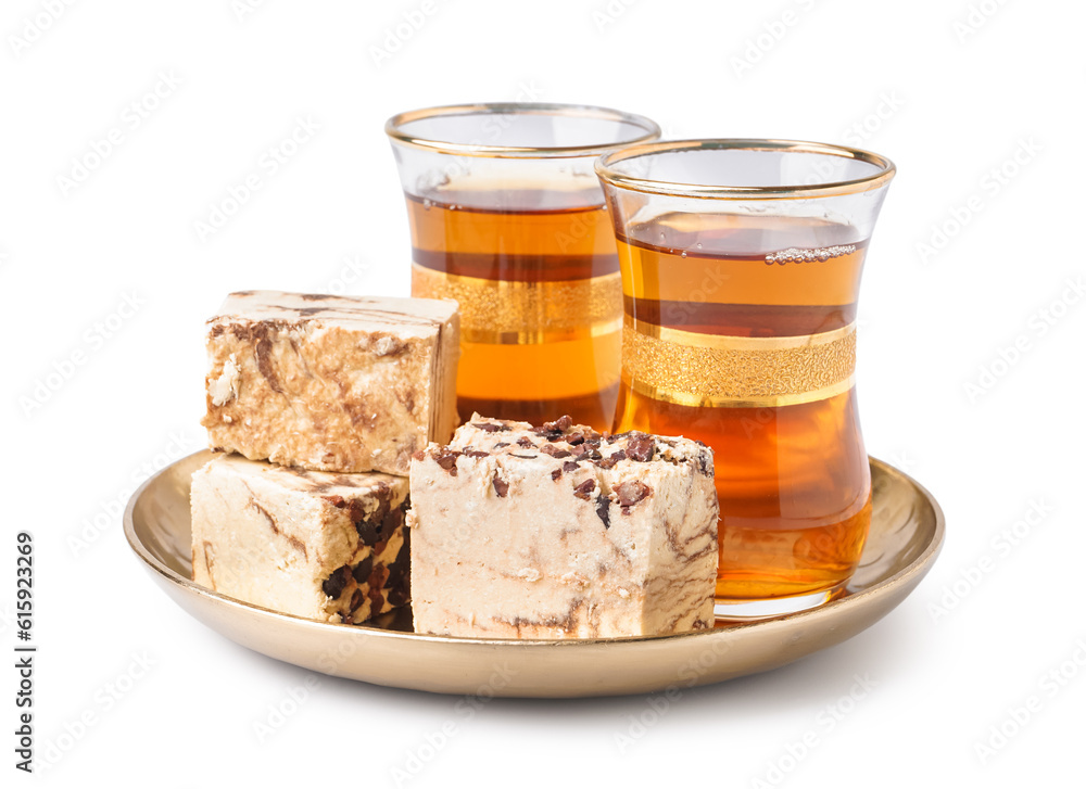 Glasses of Turkish tea and pieces of tasty marble halva on white background